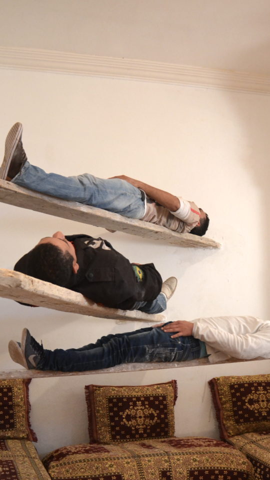 3 men laying on planks of wood